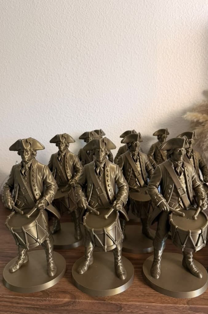 Sixteen bronze colonial drummer figures lined up on a sideboard